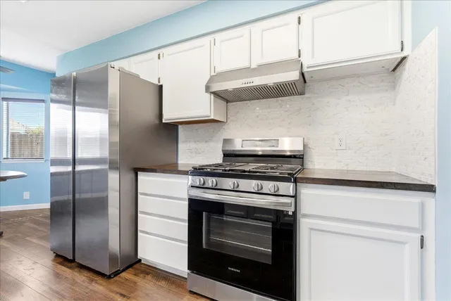 a kitchen with stainless steel appliances granite countertop a stove a refrigerator and a cabinets