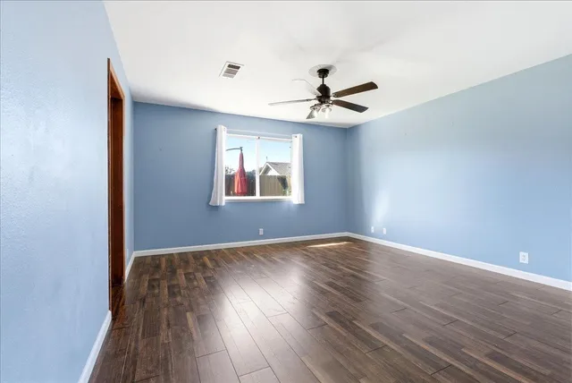 a view of empty room with wooden floor and fan