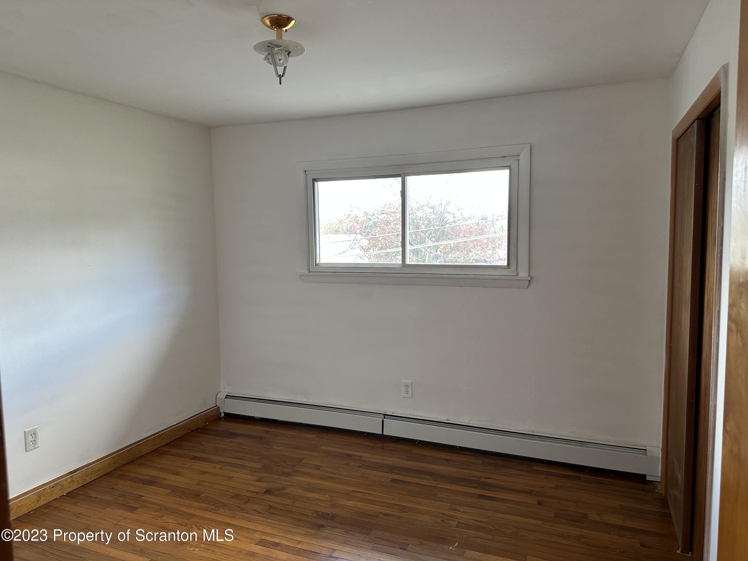 514 Morse Avenue Simpson, PA 18407 - Photo 6 of 9 an empty room with wooden floor and windows