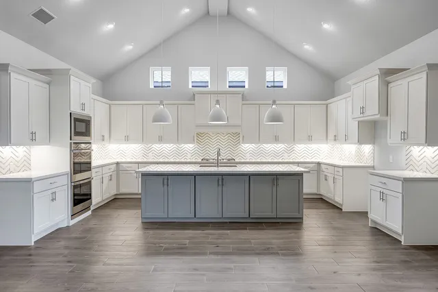 a kitchen with granite countertop a sink cabinets and wooden floor