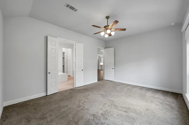 an empty room with a ceiling fan and a bathroom