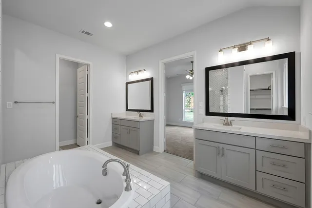 a bathroom with a tub a sink and mirror