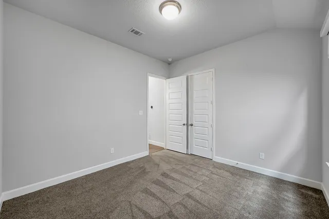 a view of an empty room with wooden floor and cabinet