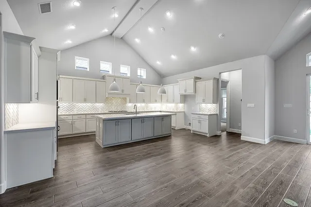 a large white kitchen with a center island wooden floor and stainless steel appliances