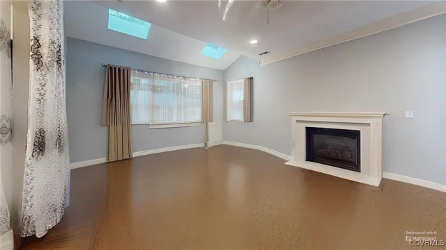 an empty room with windows and fireplace