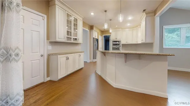 a kitchen with stainless steel appliances granite countertop a refrigerator a sink dishwasher a stove and white countertops with wooden floor