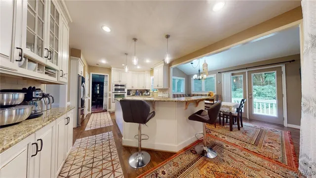 a dining hall with stainless steel appliances granite countertop a couch dining table and chairs with wooden floor