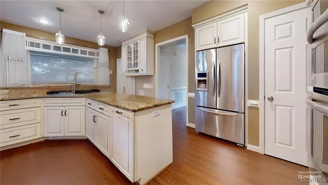 a kitchen with granite countertop a refrigerator sink and cabinets