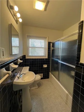 a bathroom with a sink a toilet a mirror and shower