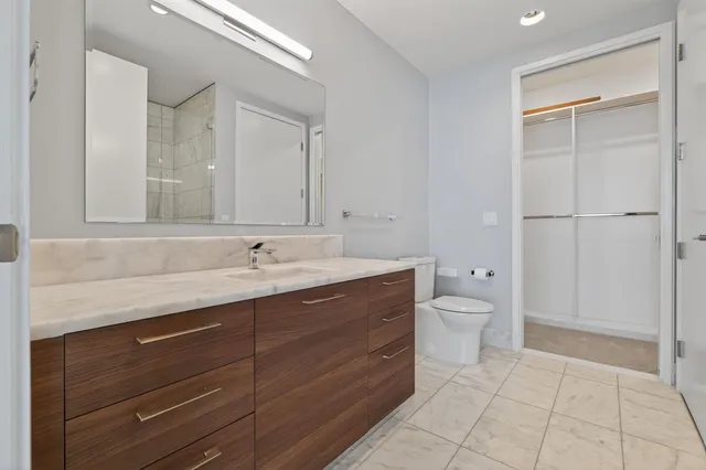 a spacious bathroom with a granite countertop sink a toilet and a mirror