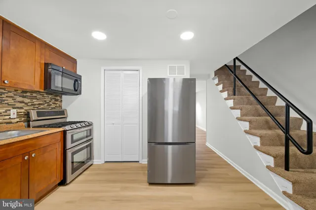 a kitchen with a refrigerator stove and wooden floor