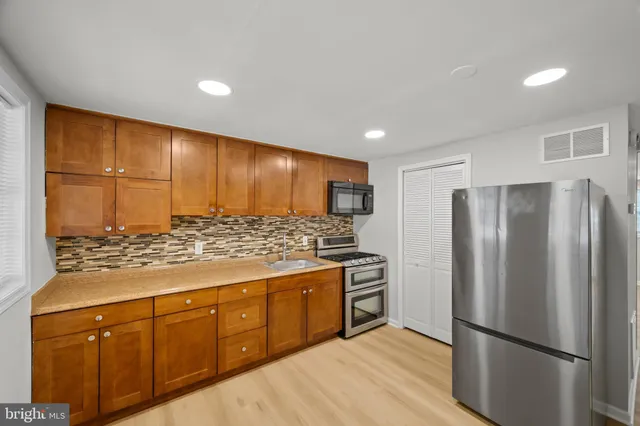 a kitchen with stainless steel appliances granite countertop a refrigerator and a stove top oven