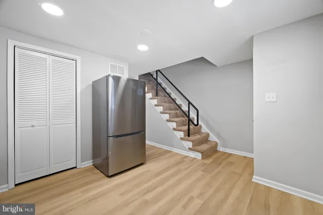 a view of an empty room with wooden floor and stairs
