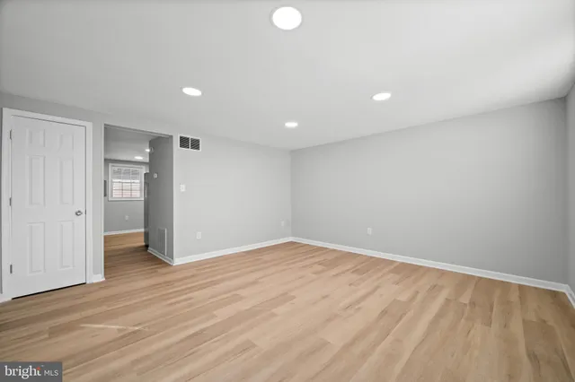 a view of an empty room with wooden floor and closet