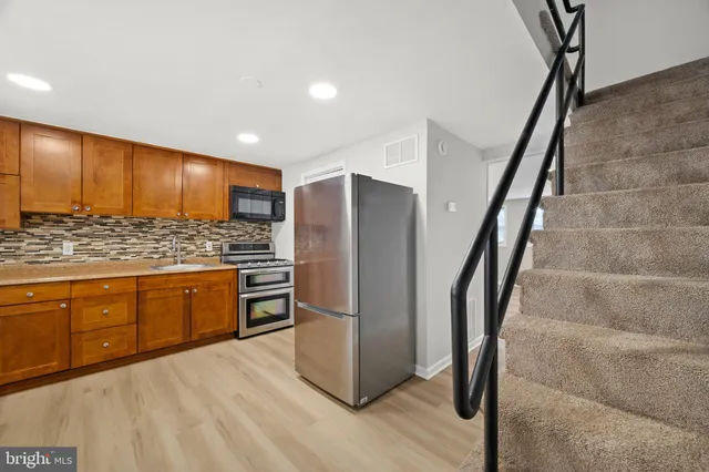 a kitchen with stainless steel appliances granite countertop a refrigerator and a stove top oven