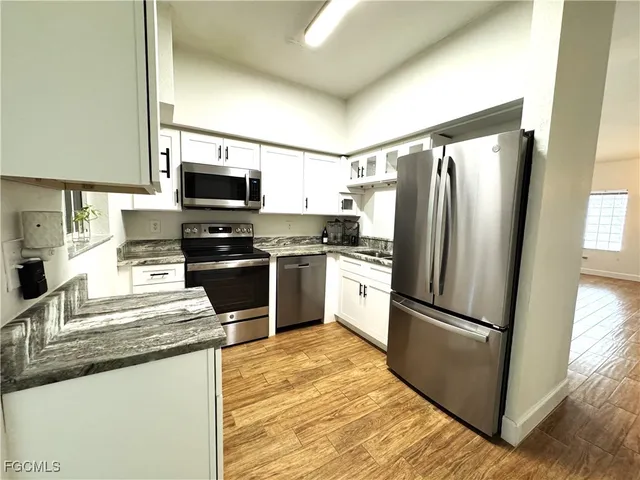 a kitchen with granite countertop a refrigerator and a stove top oven