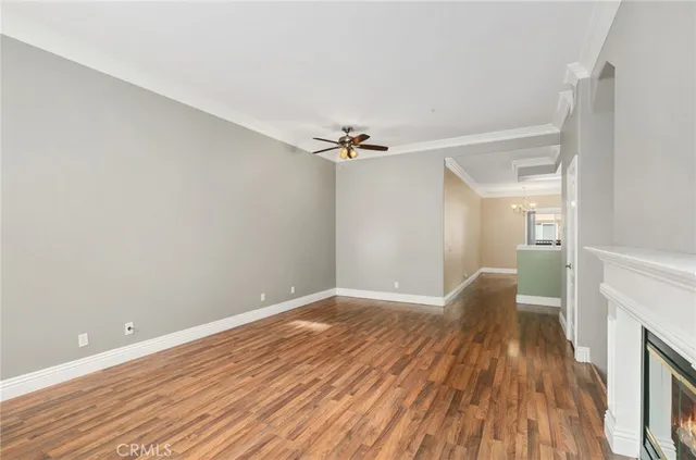 a view of a room with wooden floor a ceiling fan and a fireplace