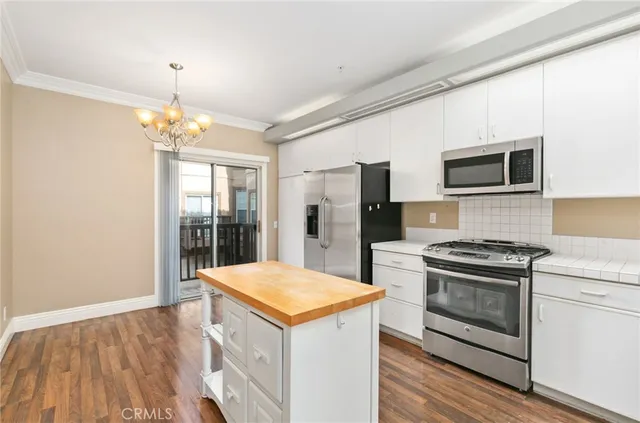 a kitchen that has a kitchen island wooden cabinets and stainless steel appliances