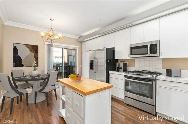 a kitchen with a stove a sink dishwasher a microwave oven and a dining table with wooden floor