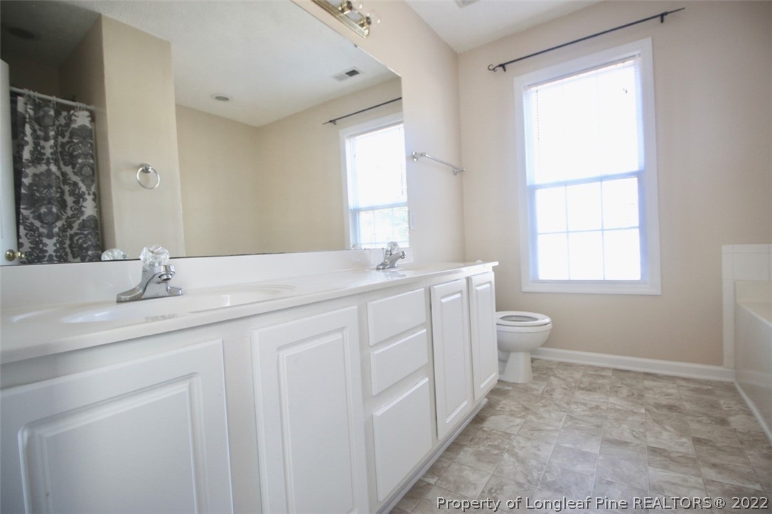 2004 Ivey Commons Road Fayetteville, NC 28306 - Photo 12 of 21 a bathroom with a double vanity sink a toilet and a window
