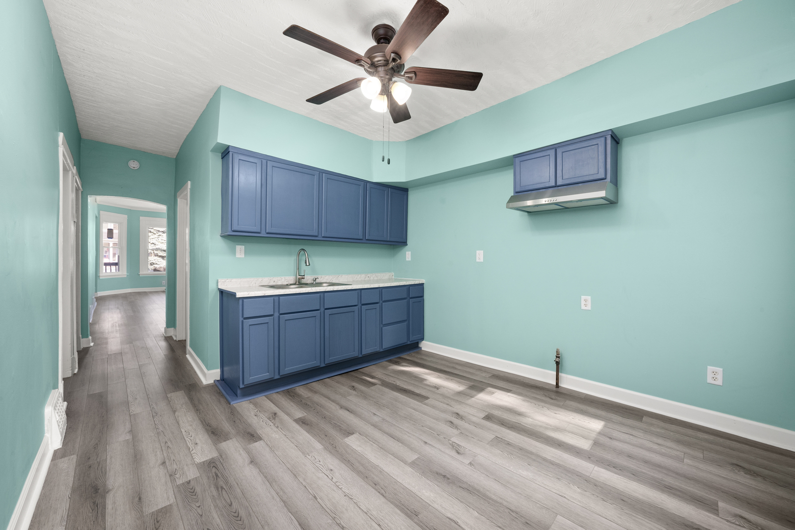 7128 South May Street Chicago, IL 60621 - Photo 7 of 32 a room with a ceiling fan and a kitchen view