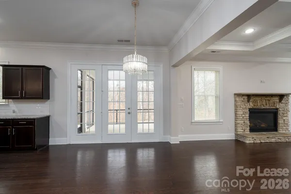 a view of an empty room with wooden floor fireplace and a window