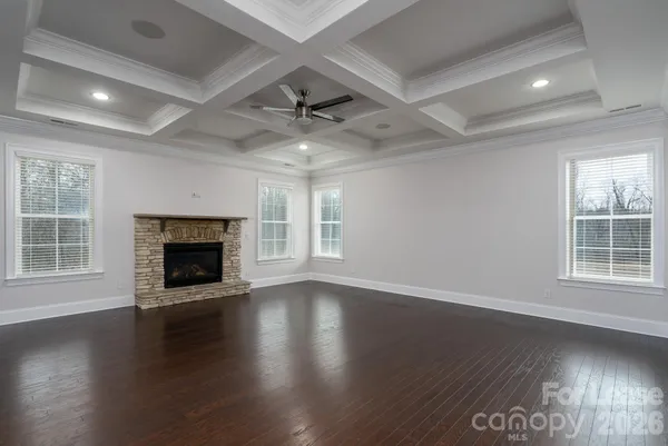 an empty room with wooden floor fireplace and windows