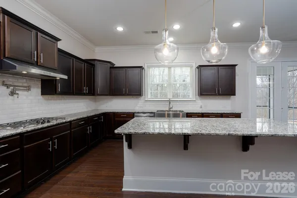 a large kitchen with granite countertop a sink a counter space stainless steel appliances and cabinets