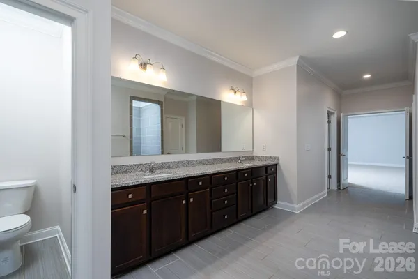a spacious bathroom with a granite countertop sink a toilet and a mirror