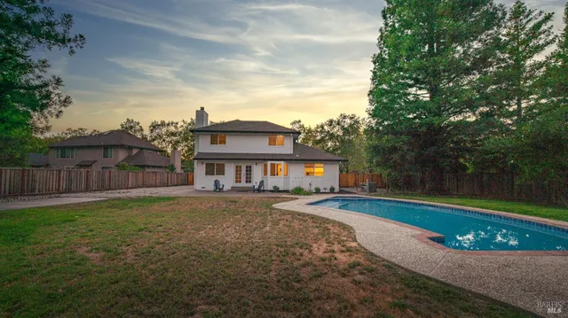 a view of a house with a big yard and large trees