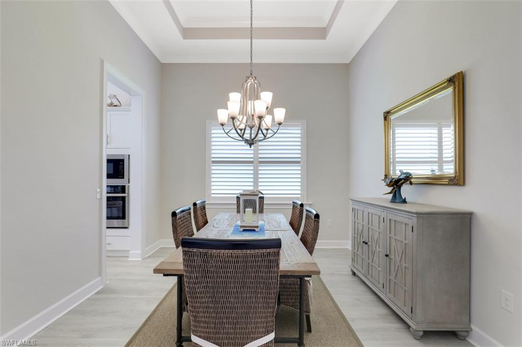 5771 Clarendon Drive Naples, FL 34113 - Photo 11 of 33 a dining room with furniture a chandelier and window