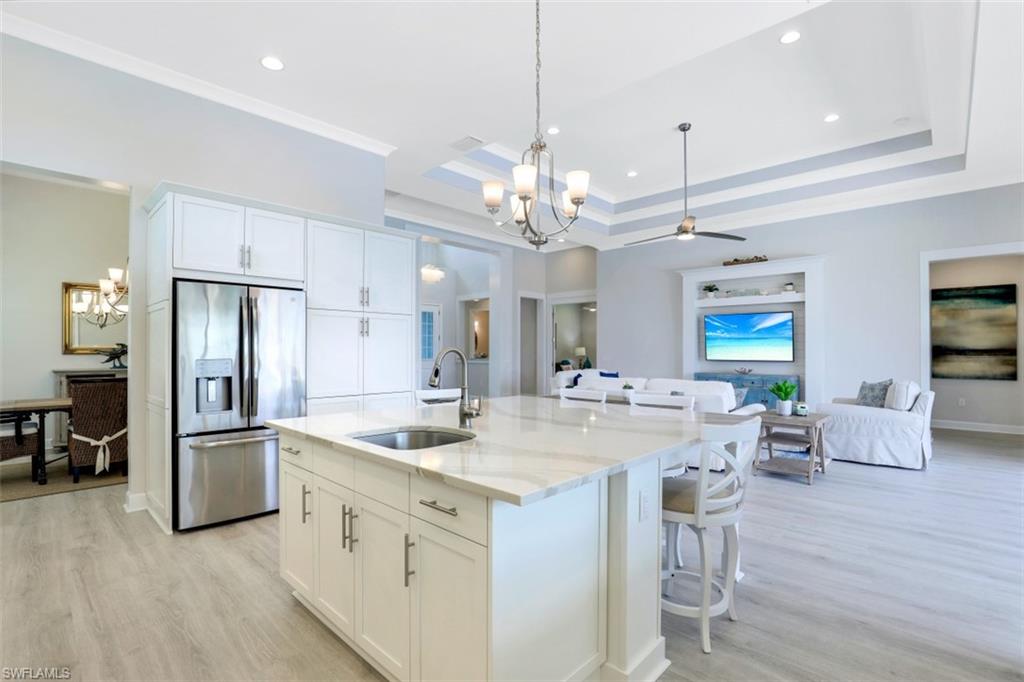 5771 Clarendon Drive Naples, FL 34113 - Photo 9 of 33 a large kitchen with kitchen island a refrigerator a stove a sink dishwasher a dining table and chairs with wooden floor