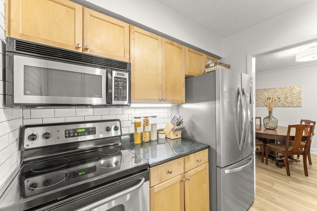 1150 Collier Road Northwest, Unit J18 Atlanta, GA 30318 - Photo 14 of 32 a kitchen with granite countertop cabinets stainless steel appliances and a counter space
