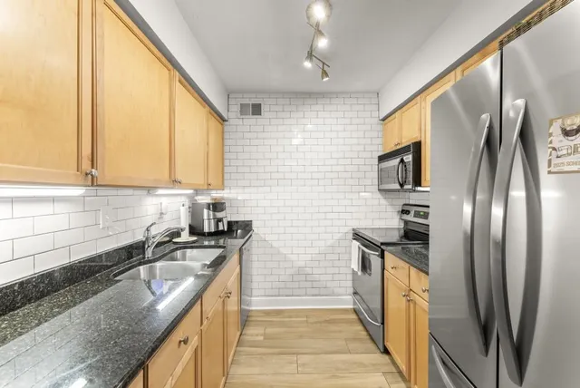 a kitchen with stainless steel appliances granite countertop a sink stove and refrigerator