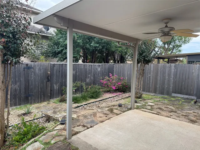 a backyard of a house with table chairs and a large tree