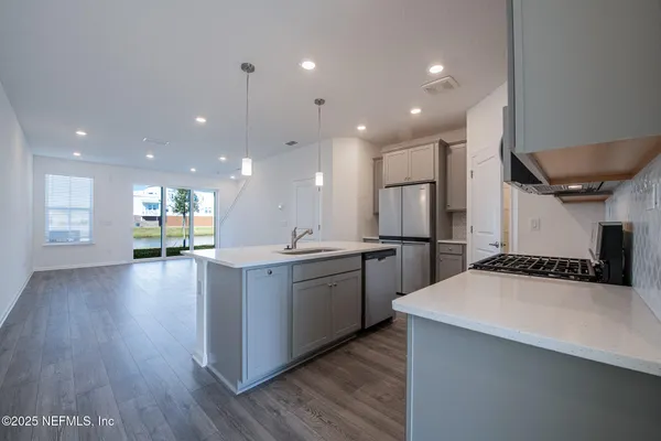 a kitchen with a sink stainless steel appliances and wooden floor