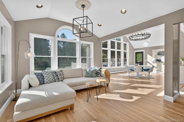 a living room with furniture a chandelier and wooden floor