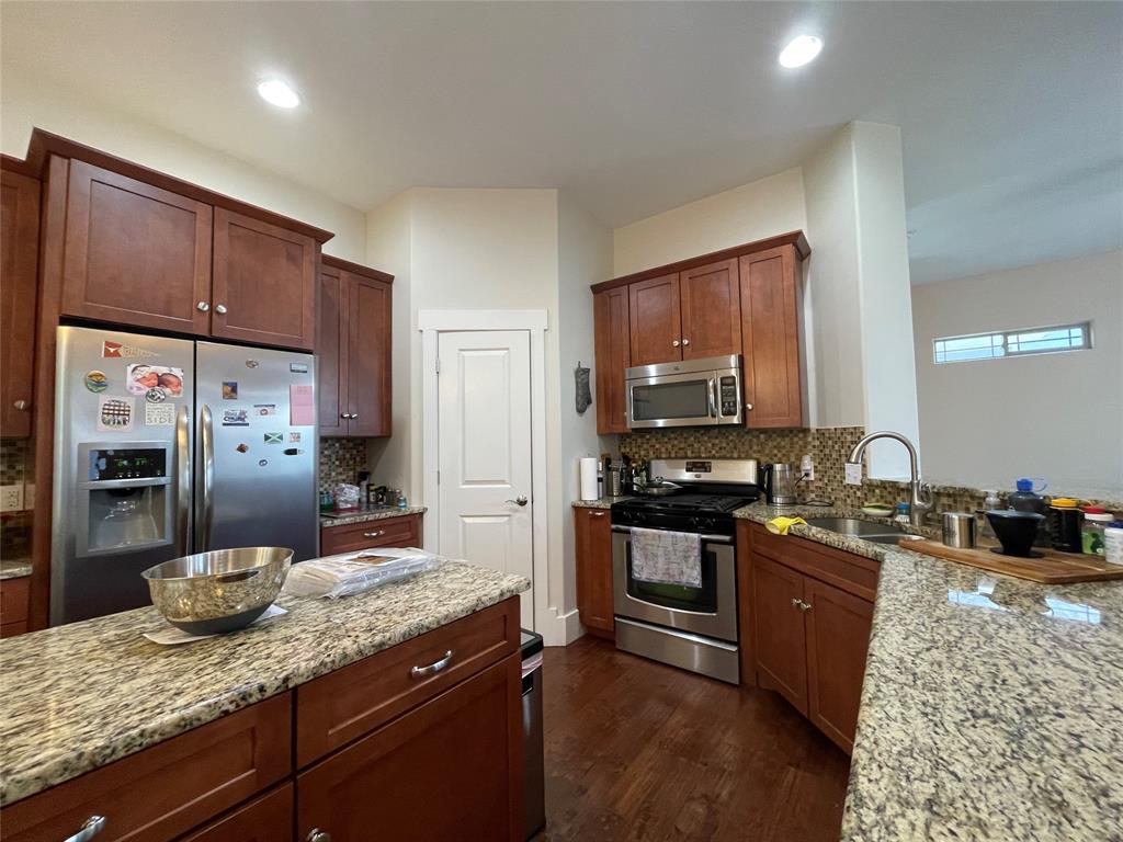 1007 Taulbee Lane, Unit B Austin, TX 78757 - Photo 11 of 36 Kitchen with stainless steel appliances, light stone countertops, dark wood finished floors, and decorative backsplash