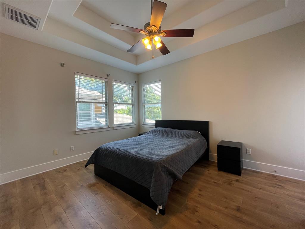 1007 Taulbee Lane, Unit B Austin, TX 78757 - Photo 14 of 36 Bedroom featuring a tray ceiling, hardwood / wood-style flooring, and a ceiling fan