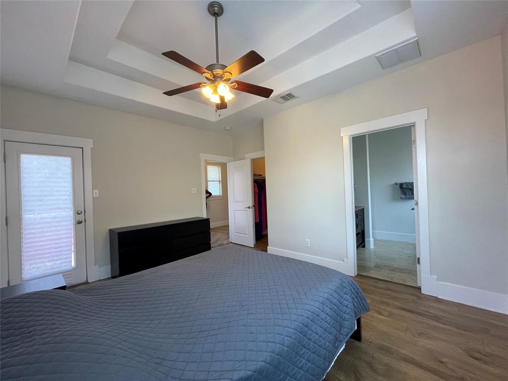 1007 Taulbee Lane, Unit B Austin, TX 78757 - Photo 15 of 36 Bedroom featuring a spacious closet, dark wood-style floors, a ceiling fan, a tray ceiling, and access to outside
