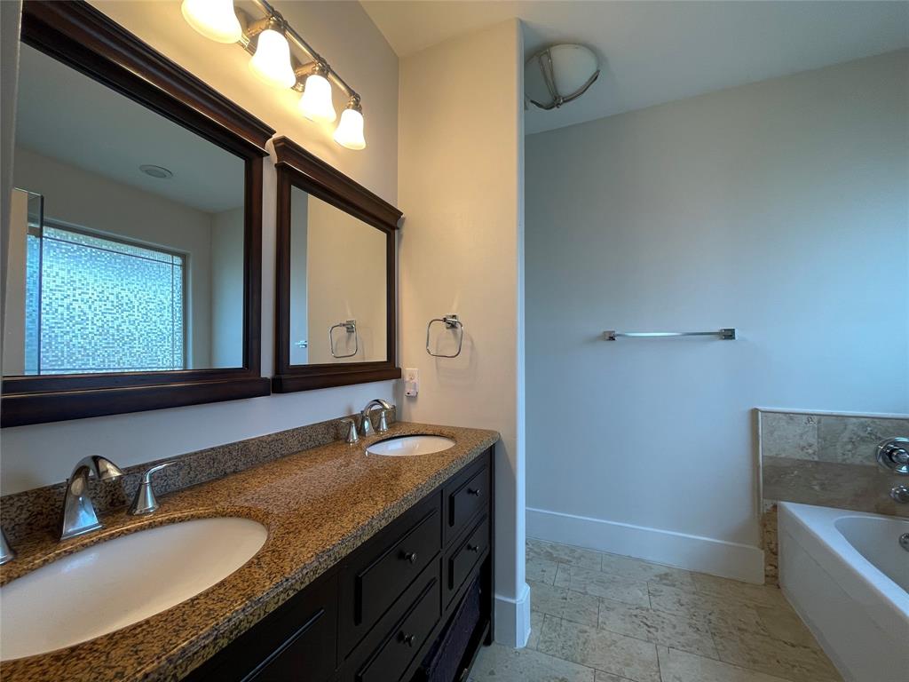1007 Taulbee Lane, Unit B Austin, TX 78757 - Photo 17 of 36 Bathroom featuring double vanity, a garden tub, and light stone finish floors