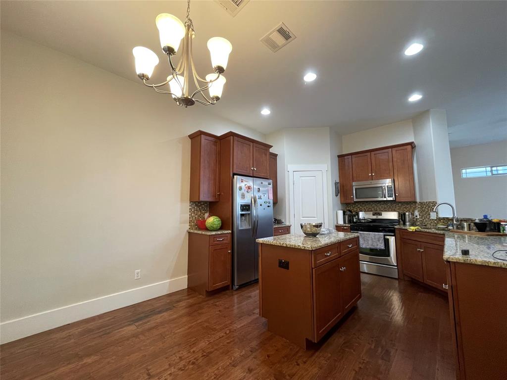 1007 Taulbee Lane, Unit B Austin, TX 78757 - Photo 9 of 36 Kitchen featuring a kitchen island, stainless steel appliances, light stone countertops, and dark wood finished floors