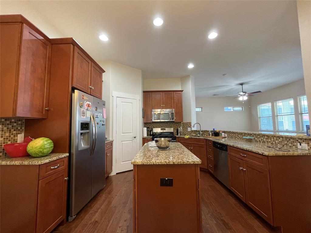 1007 Taulbee Lane, Unit B Austin, TX 78757 - Photo 10 of 36 Kitchen featuring stainless steel appliances, a peninsula, a center island, light stone counters, and wood finish cabinets