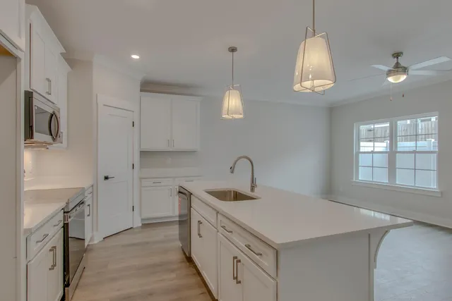 a kitchen with a sink dishwasher a stove and a refrigerator with wooden floor