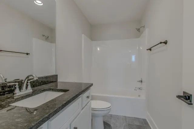 a bathroom with a granite countertop sink a toilet and shower