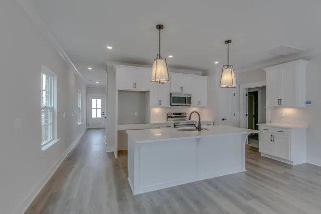 a large kitchen with stainless steel appliances kitchen island a large counter top and a wooden floors