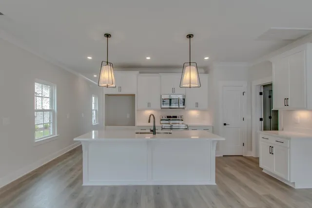 a large kitchen with stainless steel appliances granite countertop a sink a oven a center island a stove and a window