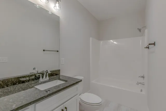 a bathroom with a granite countertop sink a toilet and shower