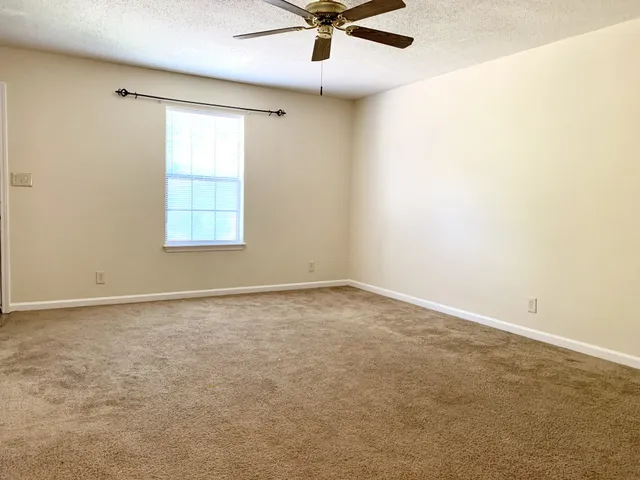 an empty room with a window and a ceiling fan