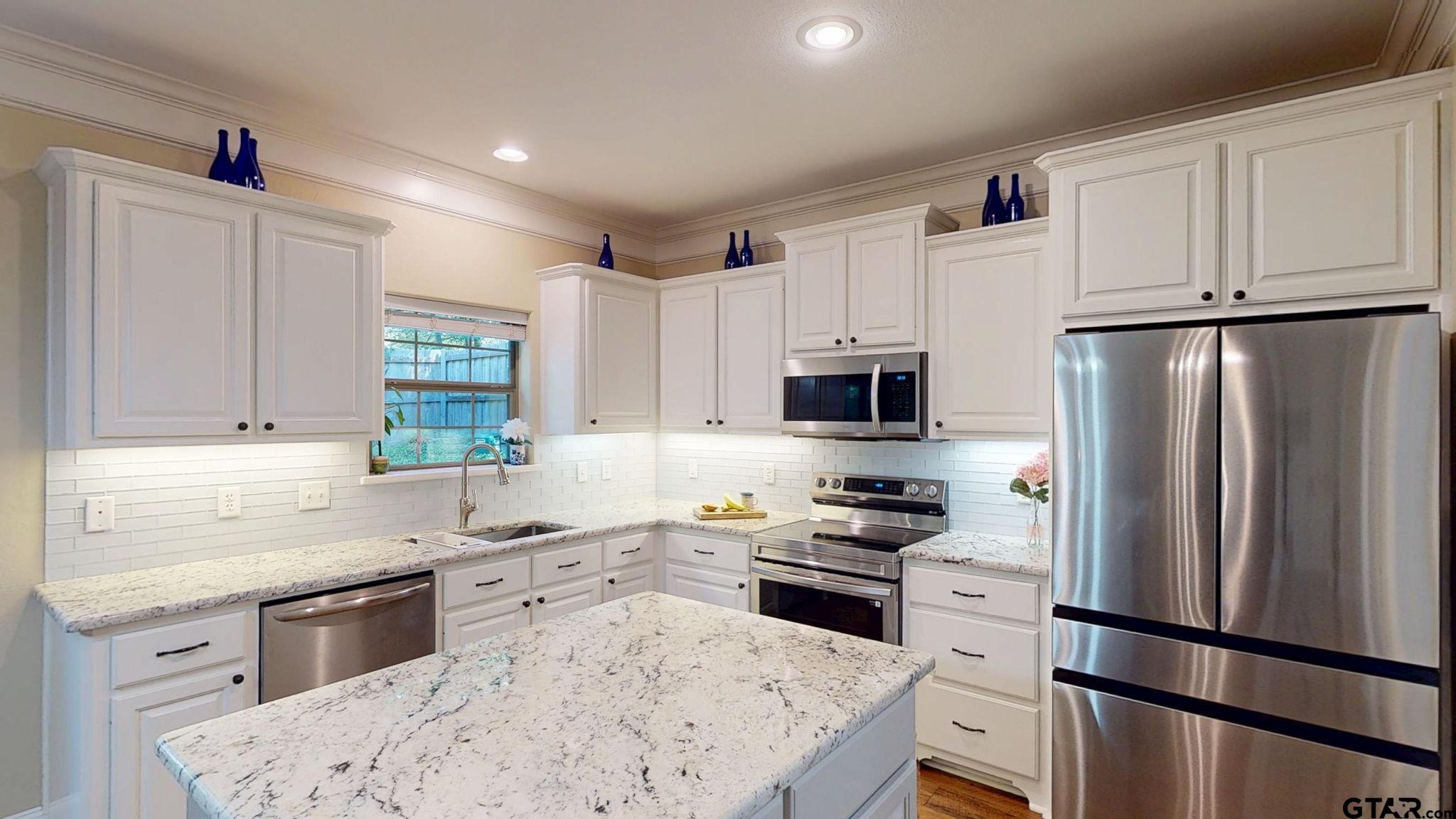 18488 Bluebird Circle Flint, TX 75762 - Photo 12 of 47 a kitchen with white cabinets sink and stainless steel appliances